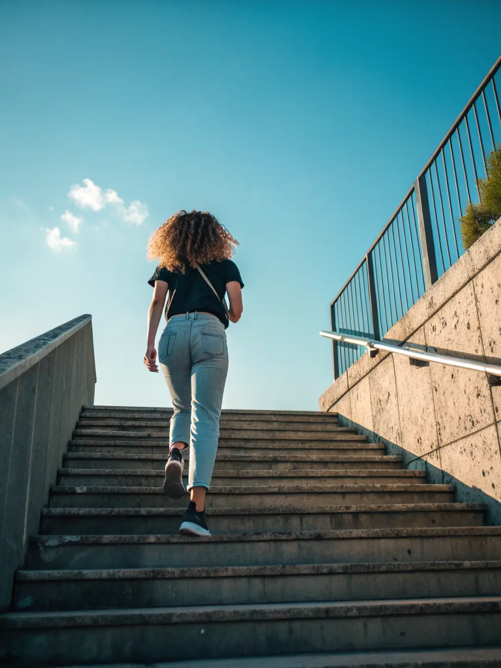An inspiring image of a person confidently climbing stairs towards a bright, sunny sky, representing personal growth and achievement.
